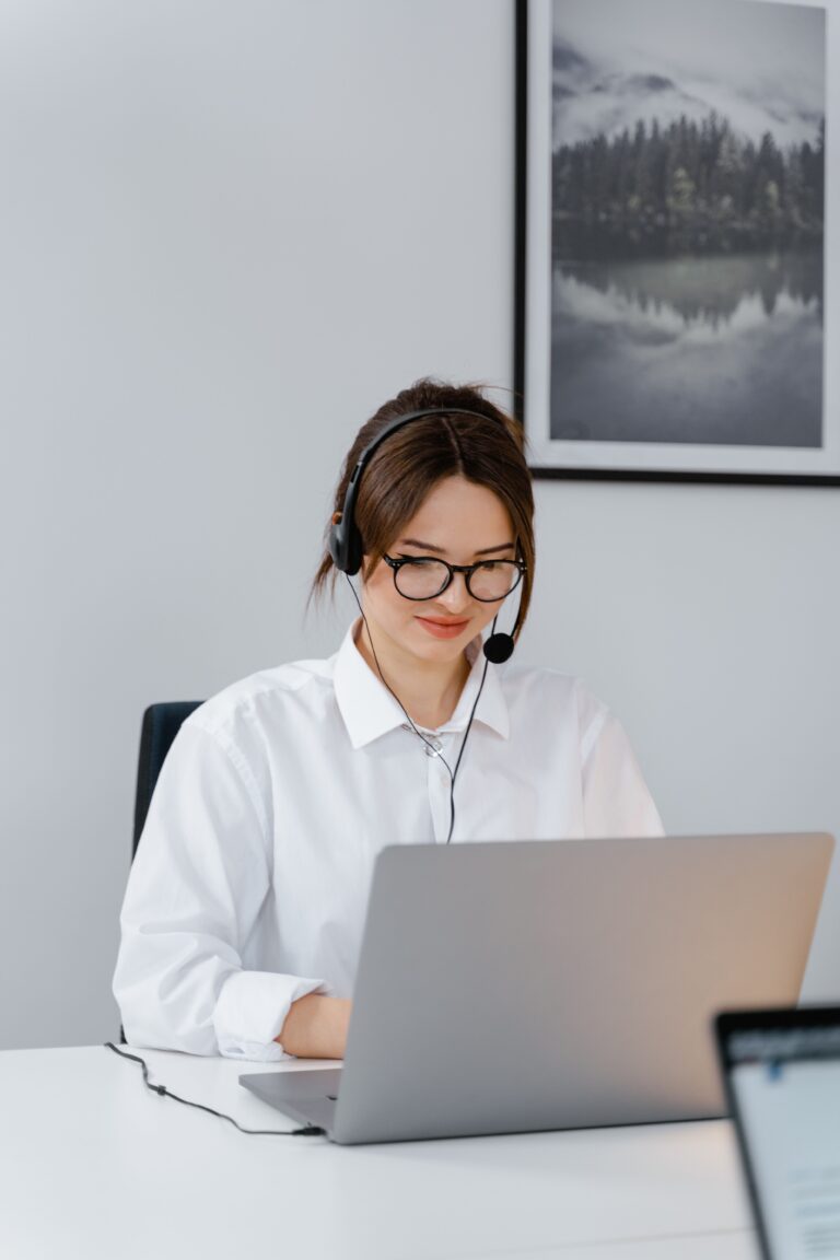 Professional woman providing customer support using a laptop and headset in a modern office.